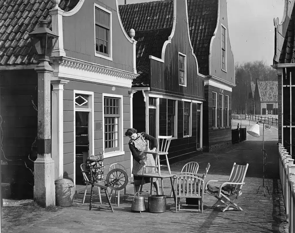 vrouw voor huizen die meubels buiten zet en een grote schoonmaak houd